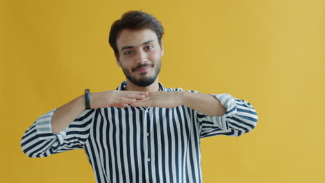 man in striped shirt posing against yellow background