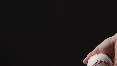 close up shot of hand throwing and catching baseball ball against black background