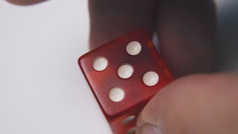 person shows red plastic dice with symbol five macro