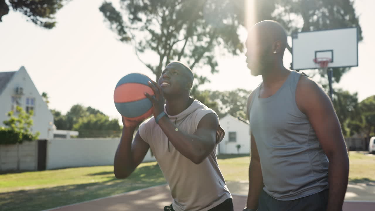 Two men playing basketball outdoors