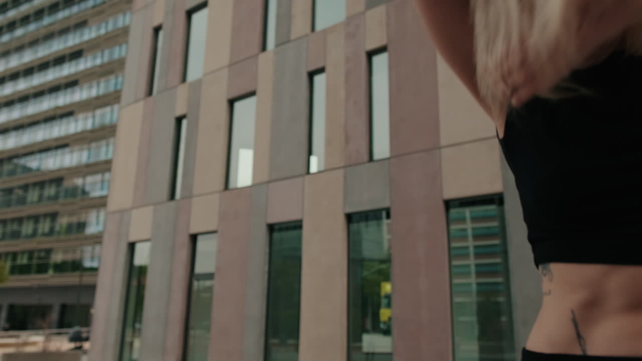 Giovane donna che balla in modo espressivo di fronte a un moderno edificio cittadino