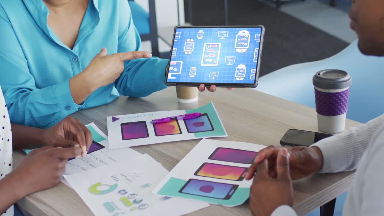 Biracial creative businesswoman using tablet with data processing on screen in office design meeting