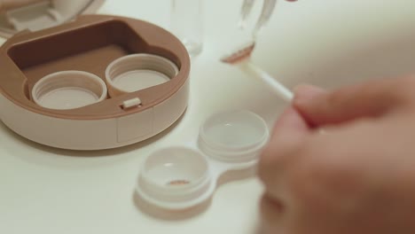 hands using tweezers to place contact lens on an applicator in order to wear it, hygienic eye care