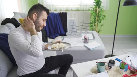 un joven soltero que vive en una casa sucia y desordenada comiendo.