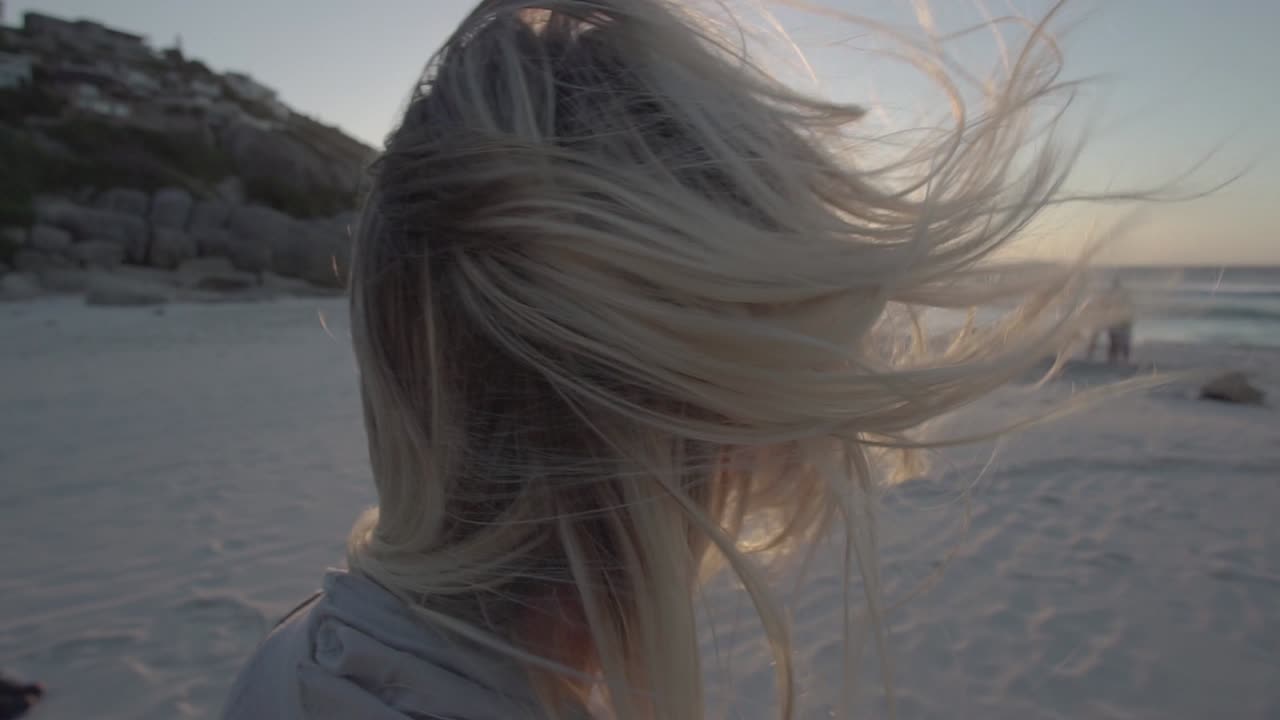 Wind blowing through the Hair of a Blonde Girl on Llandudno Beach in Cape Town, South Africa, in Slowmotion
