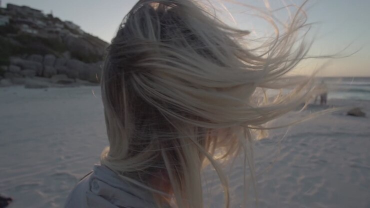Vento che soffia tra i capelli di una ragazza bionda sulla spiaggia di Llandudno a Città del Capo, Sudafrica, al rallentatore.