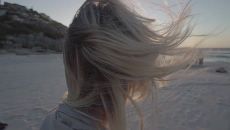 wind blowing through the hair of a blonde girl on llandudno beach in cape town, south africa, in slowmotion