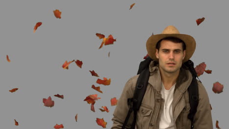 man with a hat walking under leaves falling on grey screen
