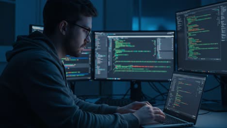 a dedicated programmer immersed in coding tasks, working intensely at a laptop surrounded by multiple monitors displaying colorful programming languages in a dimly lit environment