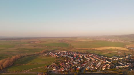 drone aéreo en movimiento izquierdo sobre casas suburbanas en un paisaje verde y plano al amanecer