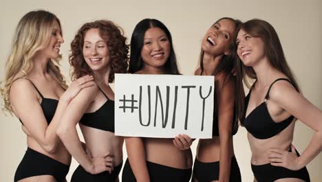 Portrait-of-group-of-cheerful-women-in-underwear-standing-in-the-studio-and-holding-a-banner.