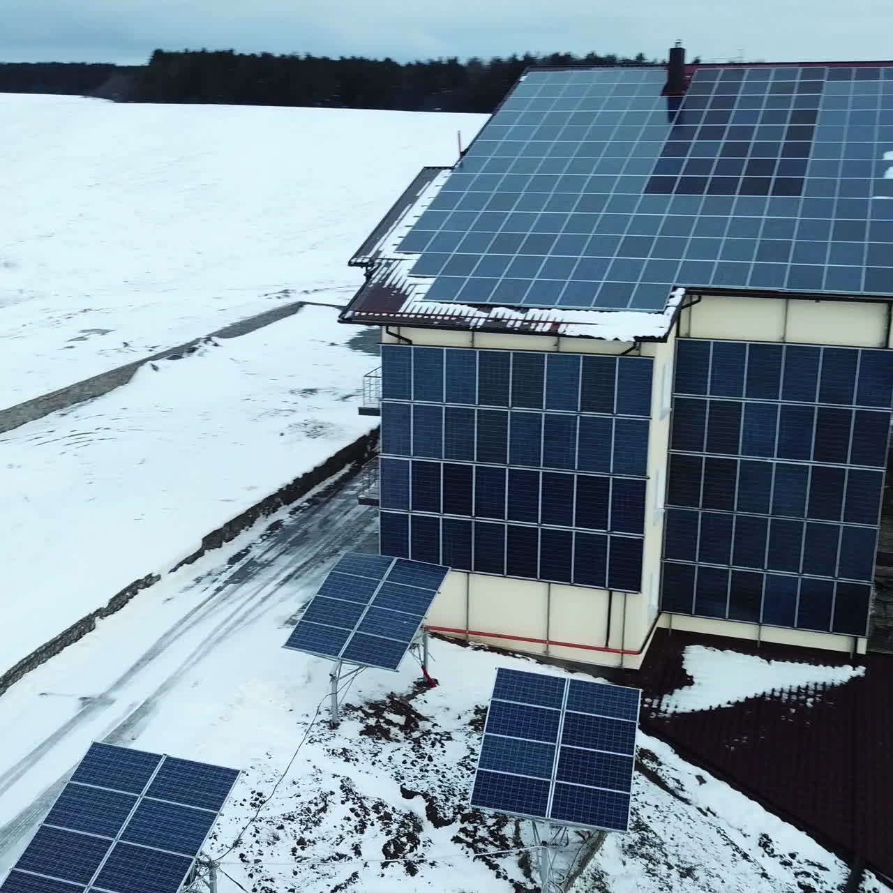 Aerial solar farm low flight in winter. Series of solar panels covered with snow.