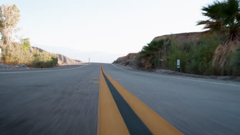 Low-angle-shot-looking-back-at-road-from-moving-vehicle