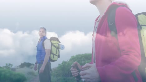 Happy-caucasian-senior-couple-hiking-in-mountains-over-fast-moving-clouds