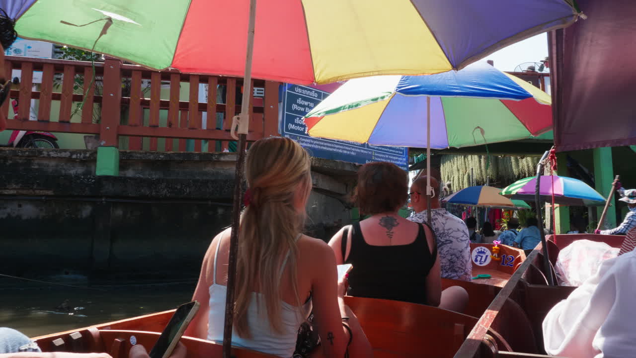 People touring a Thai floating market by boat