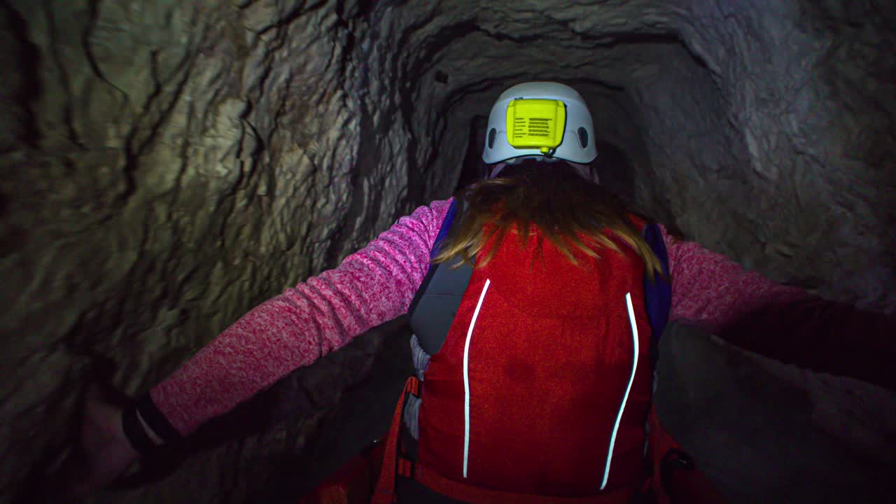 Woman in kayak find the way on narrow dark tunnel. Point of view