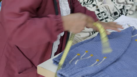 indigenous woman checking on the measures of a knitted sweater