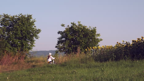 Mädchen-Im-Weißen-Kleid-Schiebt-Fahrrad-In-Ländlicher-Landschaft-Zur-Goldenen-Stunde-In-Zeitlupe