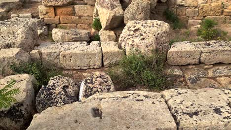 Tilt-up-from-ancient-sundial-engraved-in-rock-to-Greek-temple-at-Selinunte-archaeological-park-in-Sicily,-Italy