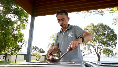 man cooks steaming vegan food on outdoor hot plate, slow motion wide shot