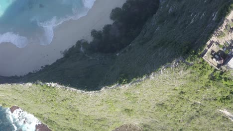 Nusa-Penida-island-Kelingking-Beach-in-Indonesia-T-Rex-peninsula-with-descending-cliff-staircase,-Aerial-overhead-rotation-reveal-shot