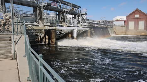 walking along sidewalk towards river dam with water flowing in slow motion.