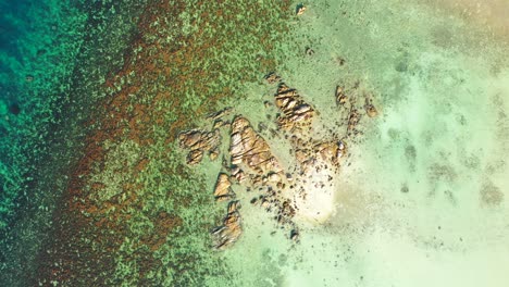 Textura-Del-Mar-Con-Hermosos-Acantilados-Naturalmente-Derrumbados-Por-Aguas-Claras-De-Una-Laguna-Turquesa-Con-Arrecifes-De-Coral-En-Fondos-Marinos-Rocosos,-Malasia