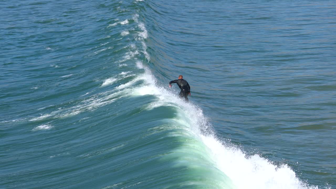 Surfer riding a wave at Pismo Beach, California. 4K action footage from above.