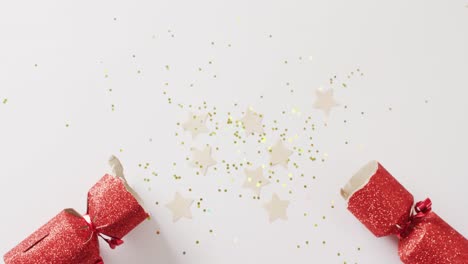 video of red christmas cracker, stars and decoration with copy space on white background