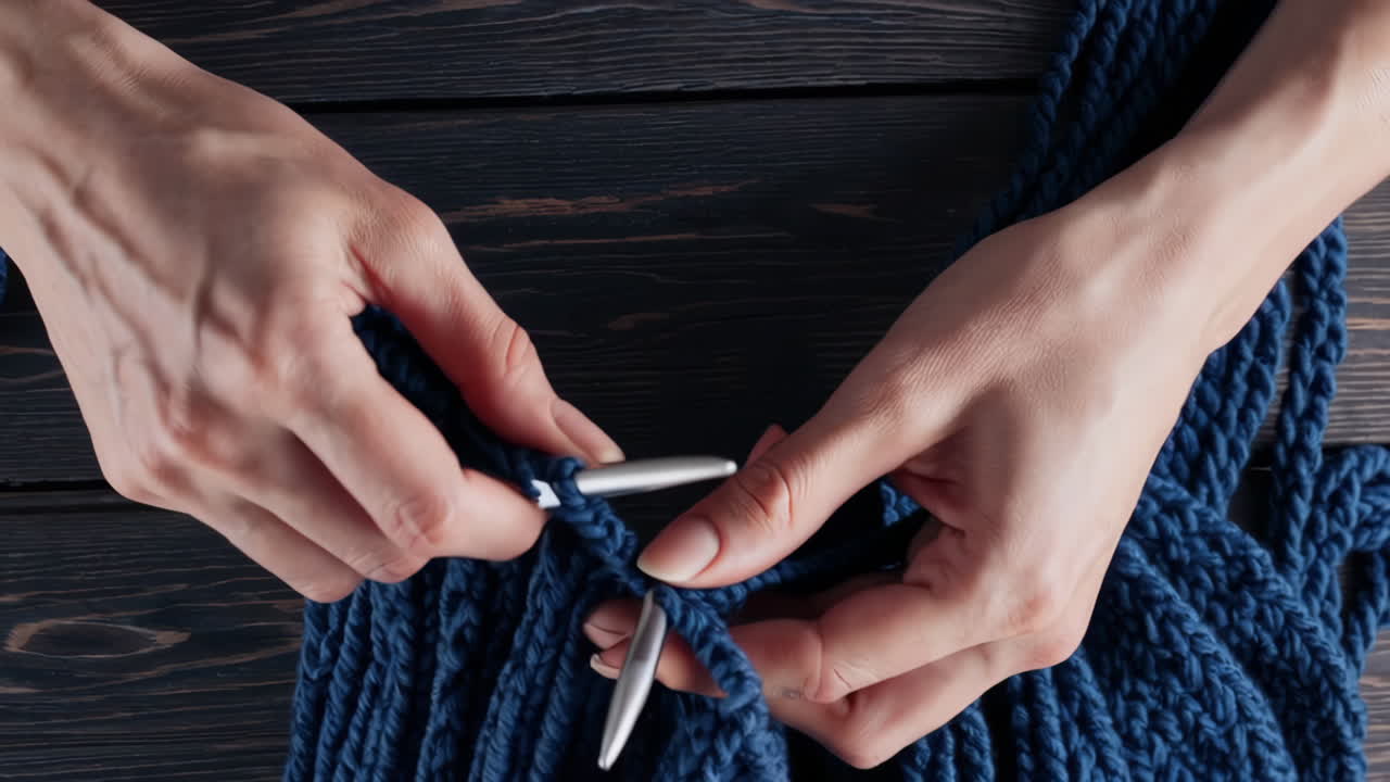 Close-up of Hands Knitting a Blue Fabric with Needles