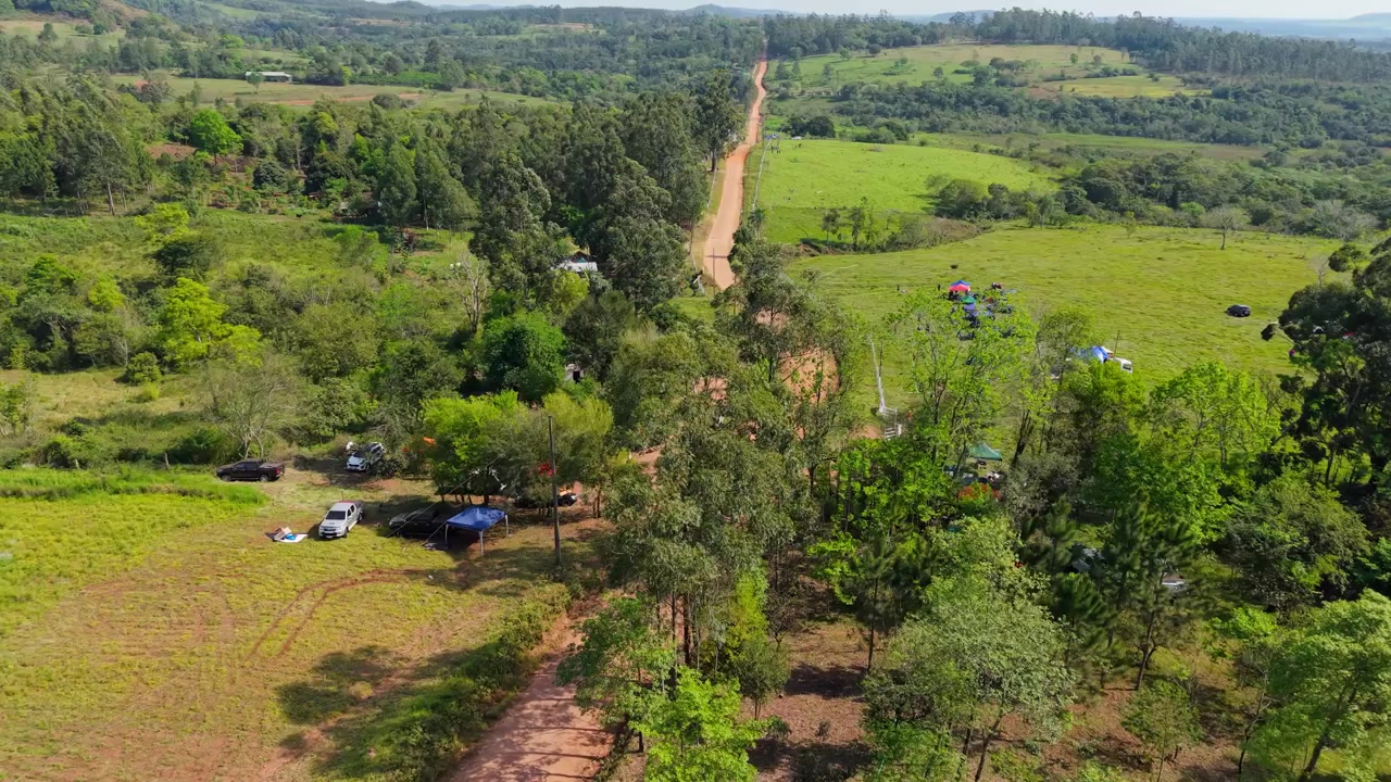 Grus rallyvej, der slynger sig gennem grønt landskab nær Nueva Alborada, Paraguay, luftfoto, etablerende mellembillede