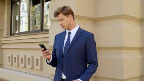 portrait of serious business man using mobile phone outdoors