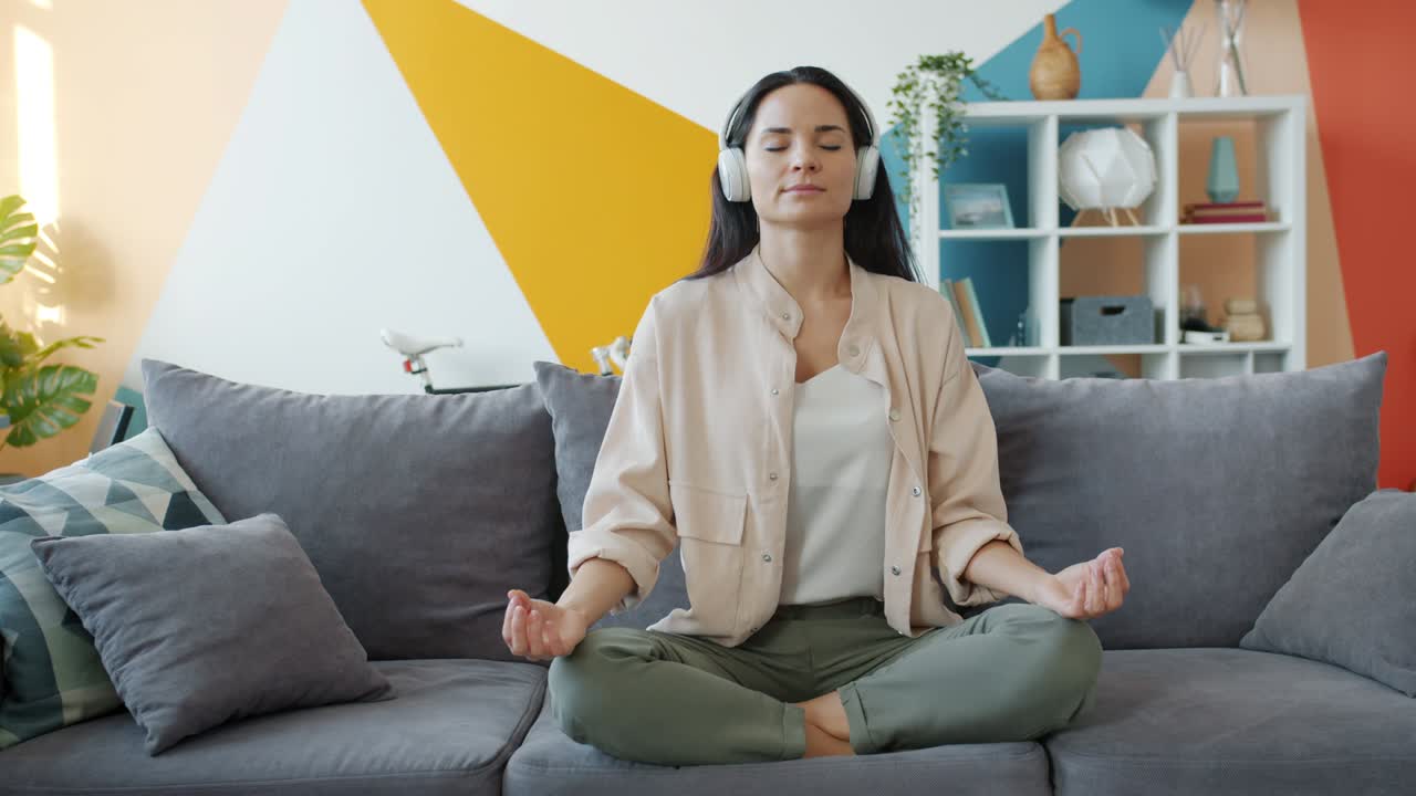 movimiento lento de chica feliz en auriculares escuchando música y relajándose en posición de loto