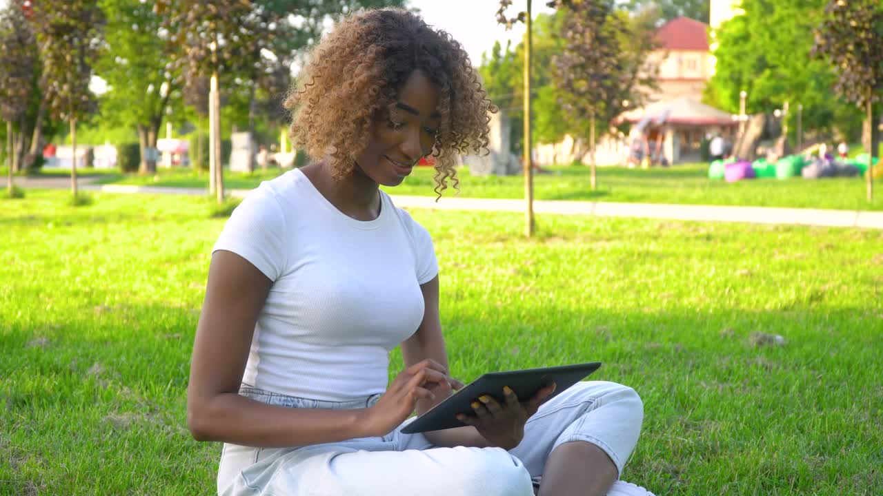 Young african american woman using tablet in park. Online learning concept
