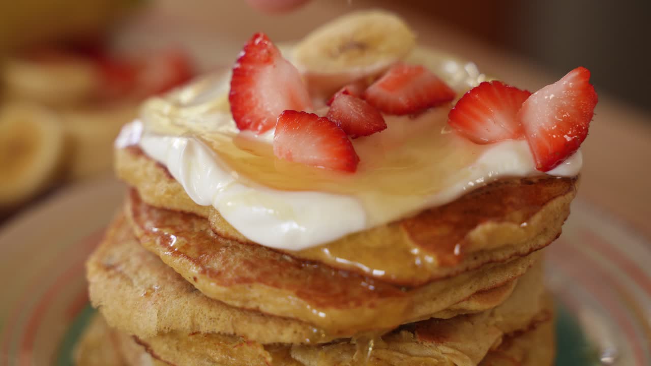 신선한 딸기와 바나나를 얹은 꿀로 덮인 크레페 더미