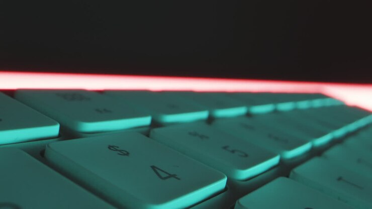 Close-up tracking shot over the individual keys of computer keyboard in red blue technical light