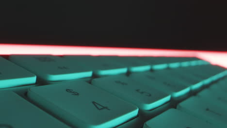 close-up tracking shot over the individual keys of computer keyboard in red blue technical light