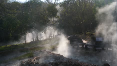 huge clouds of steam rise quietly between the natural pai hot springs on an early summer morning that tourists like to flock to