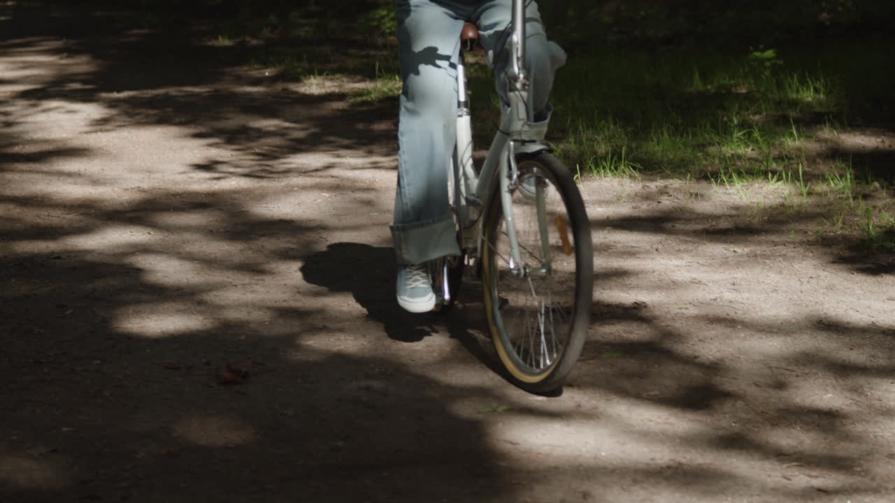 Woman Riding Bicycle on Dirt Road in Forest