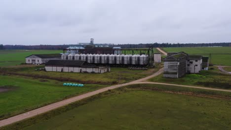 various farm buildings aerial view rising overlooking shiny steel silo containers on rural agricultural farmland