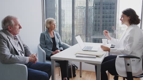 senior couple meeting female doctor for consultation in hospital office