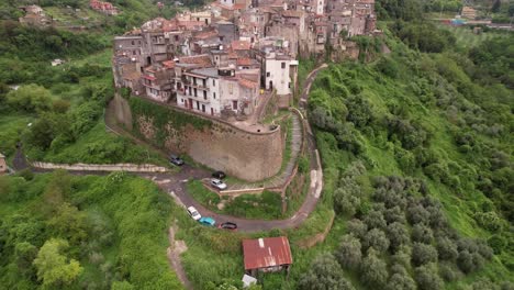 Tourist-Steht-Auf-Der-Mauer-Eines-Kleinen-Dorfes-Auf-Einem-Schmalen-Bergrücken-Im-Grünen-Tal