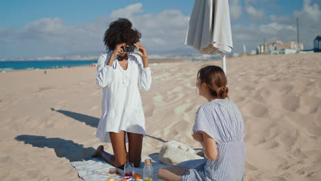 Amigos-Felices-Haciendo-Fotos-En-La-Playa-De-Arena.-Dos-Amigas-Saliendo-Juntas