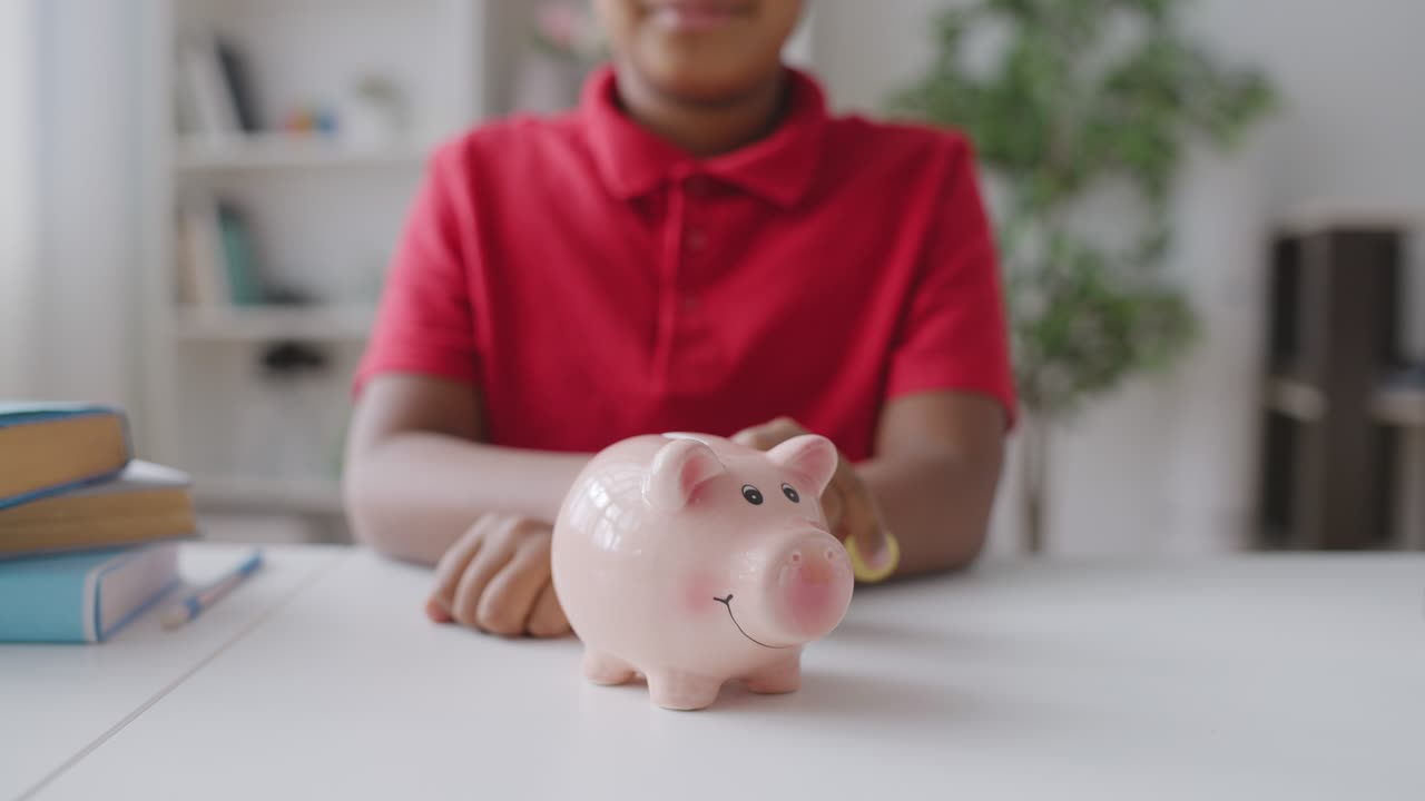 School kid saving money, putting coin in piggybank on the table, financial plan