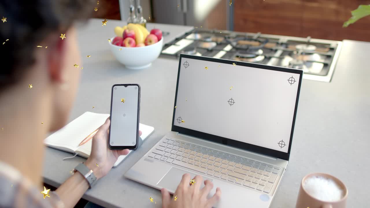 Man using phone laptop at counter tapping phone starting marks for work stars drifting over screens