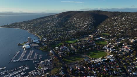mountains covered with houses in hobart city in tasmania, orbital drone shot