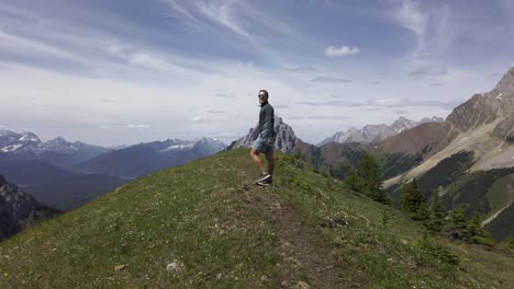 Hiker-walking-on-top-of-mountain-plane-cheering-Rockies,-Kananaskis,-Alberta-Canada