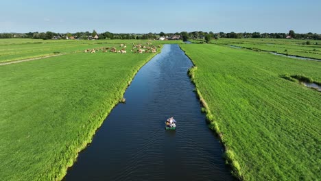 Toma-Aérea-De-Drones-De-Un-Bote-Pequeño-En-Un-Canal-De-Pólder-Holandés