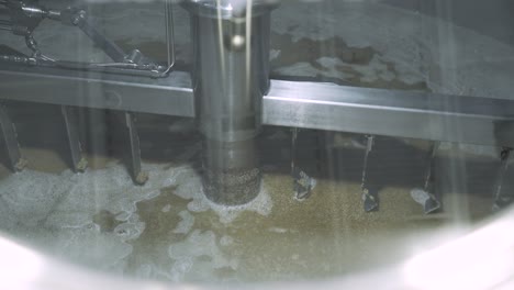 churning barley grain in brewery silo for beer production, close up