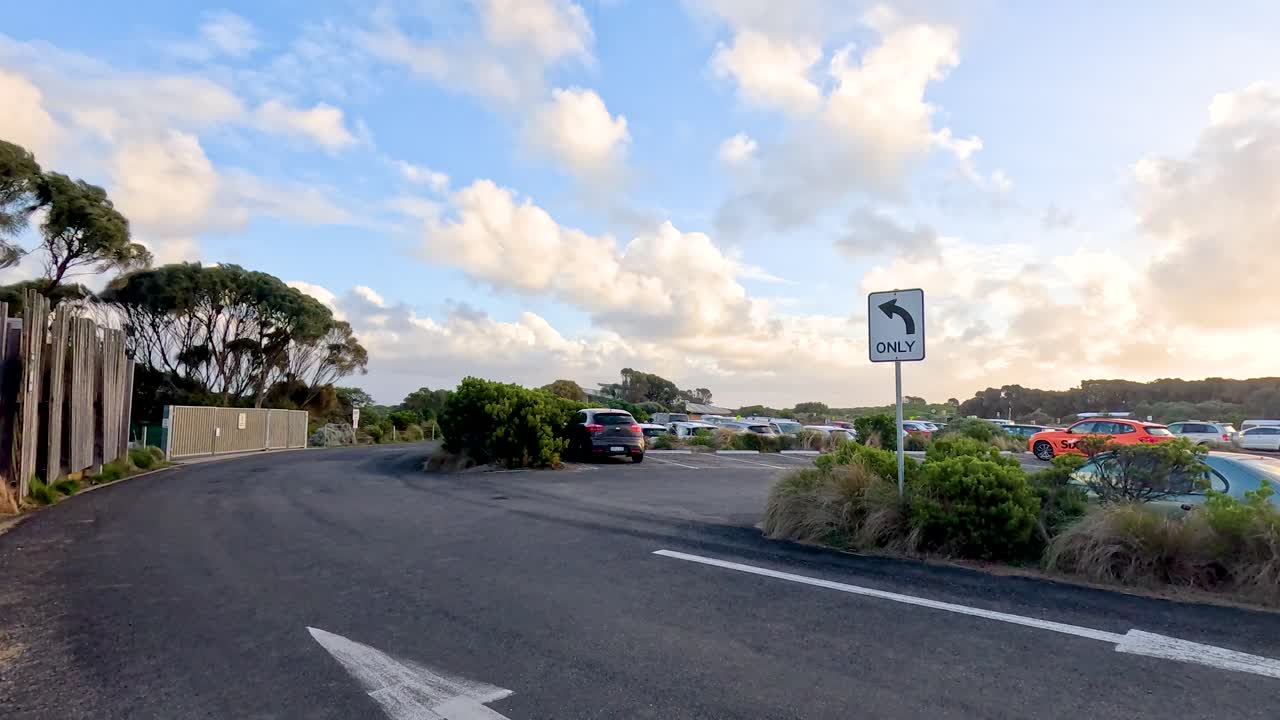 부드럽고 황금색 조명으로 포착된 활기찬 하늘과 자연 환경을 가진 울창한 해안 주차장을 가로질러 조용한 드라이브